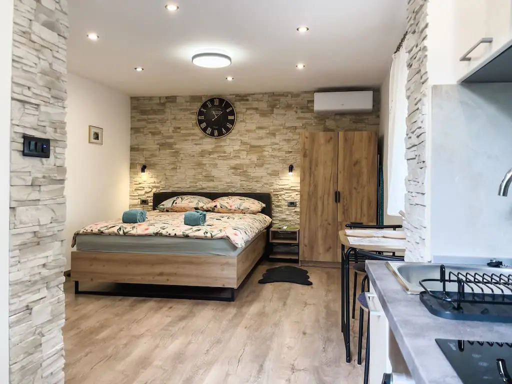 Studio with stone accent wall, bed and kitchenette